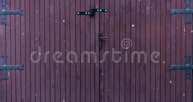 在一个旧的带有大金属铰链的木制车库门前，冬天大雪花飘落的<strong>延时视频</strong>。 4k